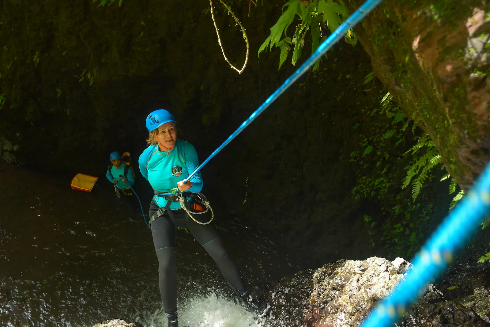 A canyoner descending a rope beside a waterfall in a North Bali canyon