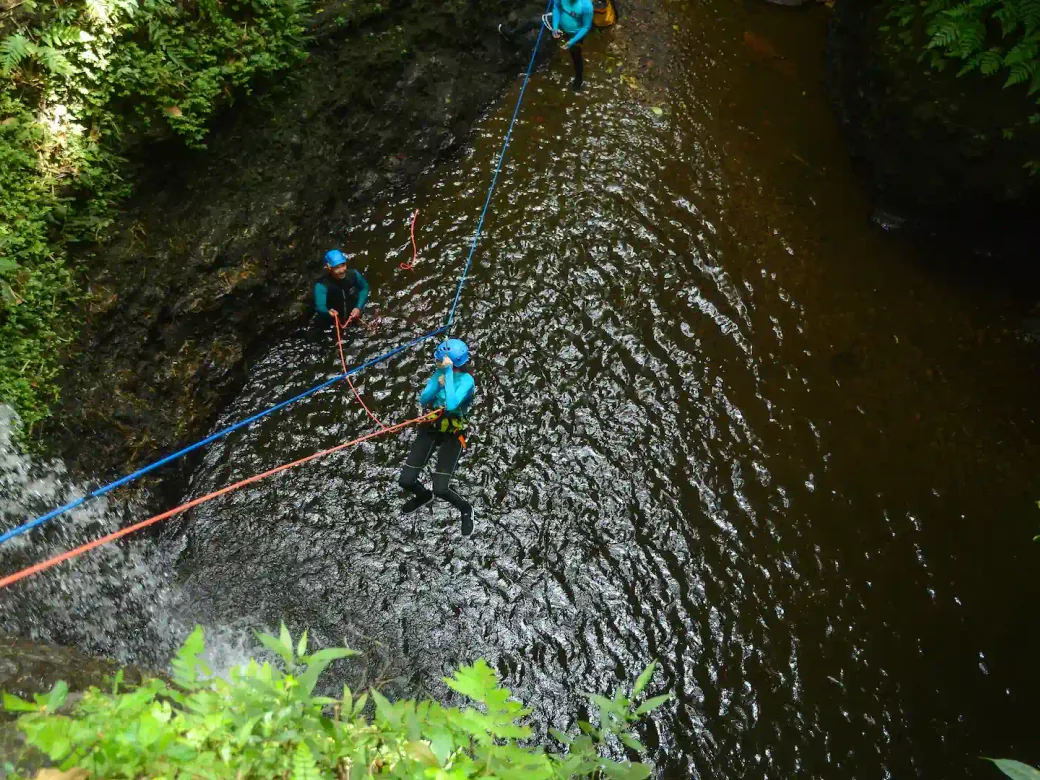 Canyoners ziplining into a natural pool in a North Bali canyon.