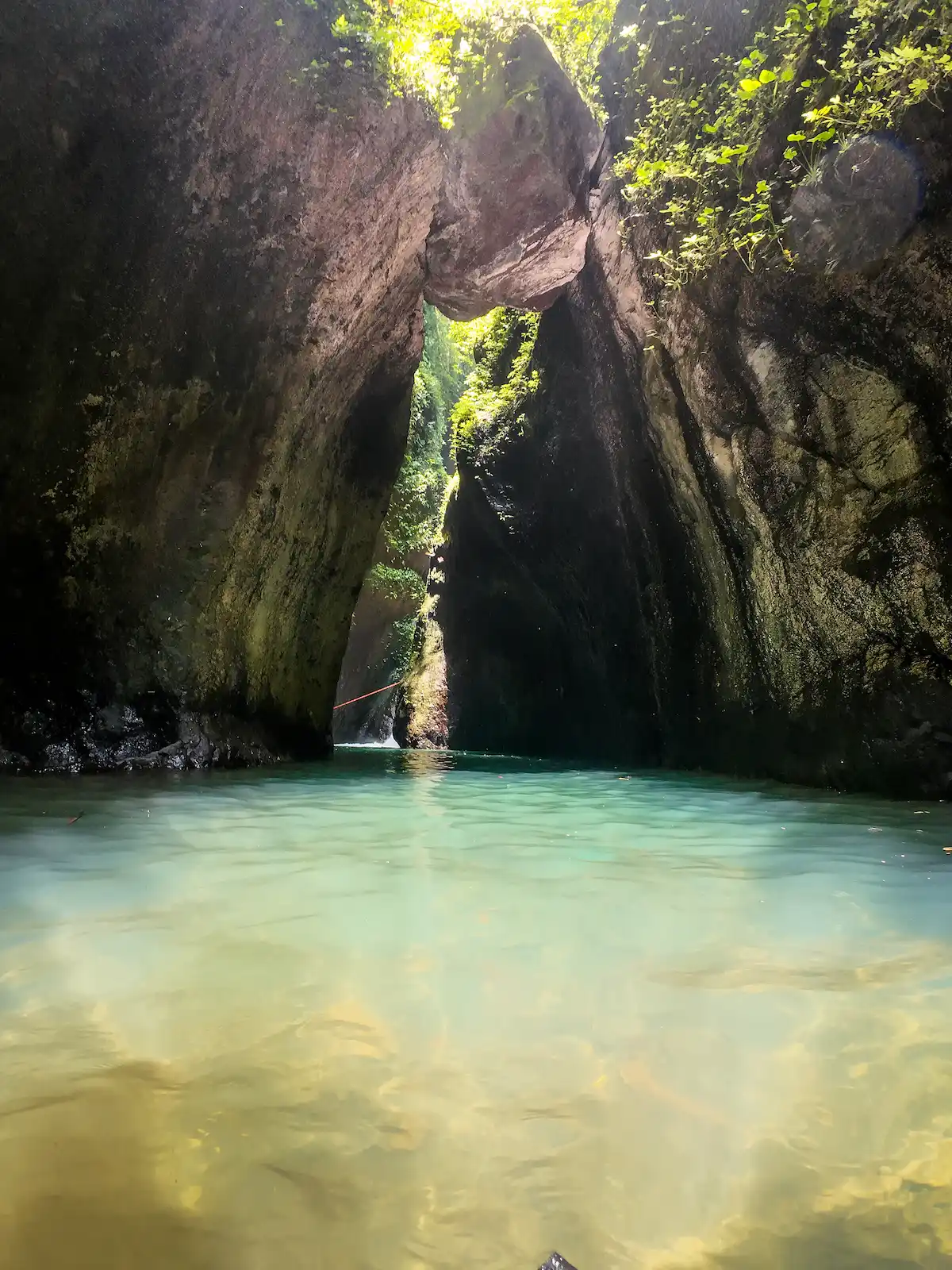 A deep turquoise pool beneath a huge natural rock arch