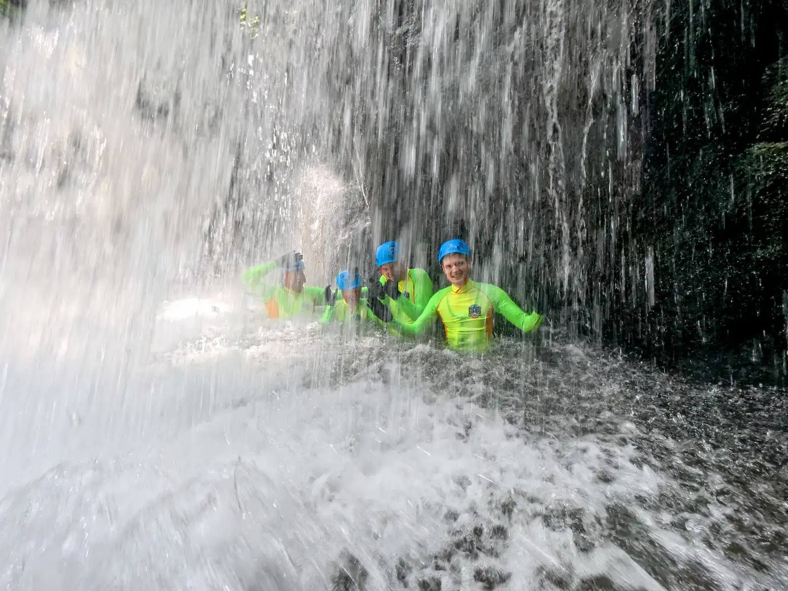 Guest standing under a powerful waterfall with arms wide open