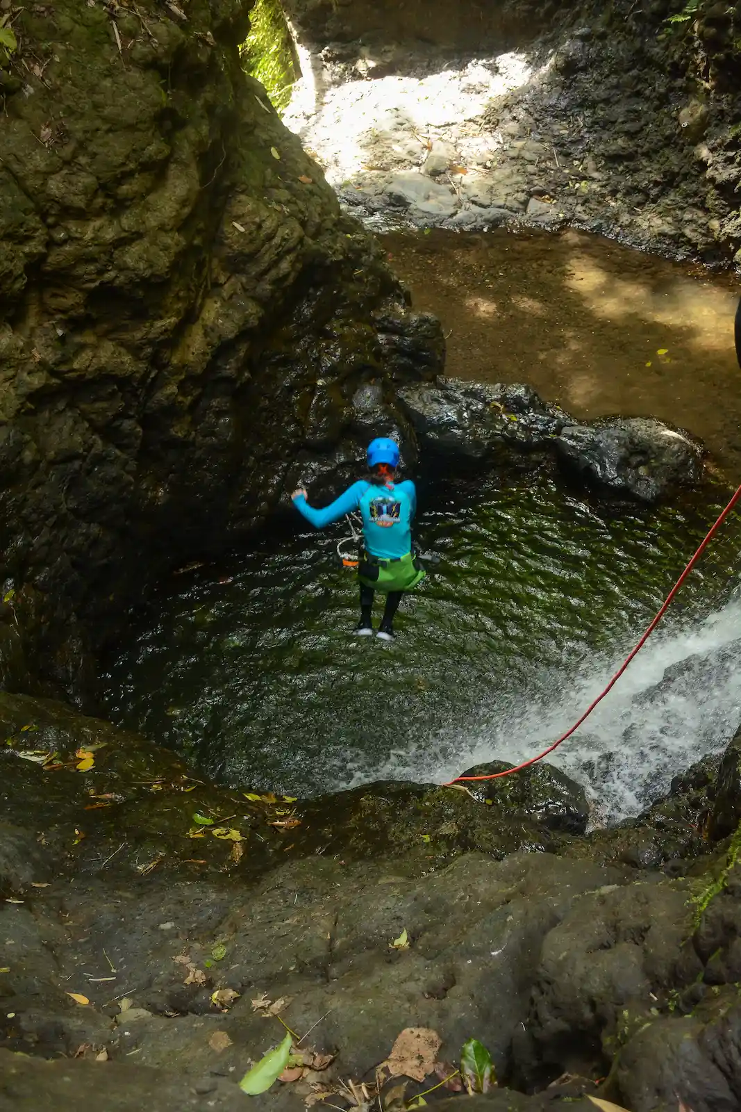 Guest being lowered into a deep emerald canyon pool