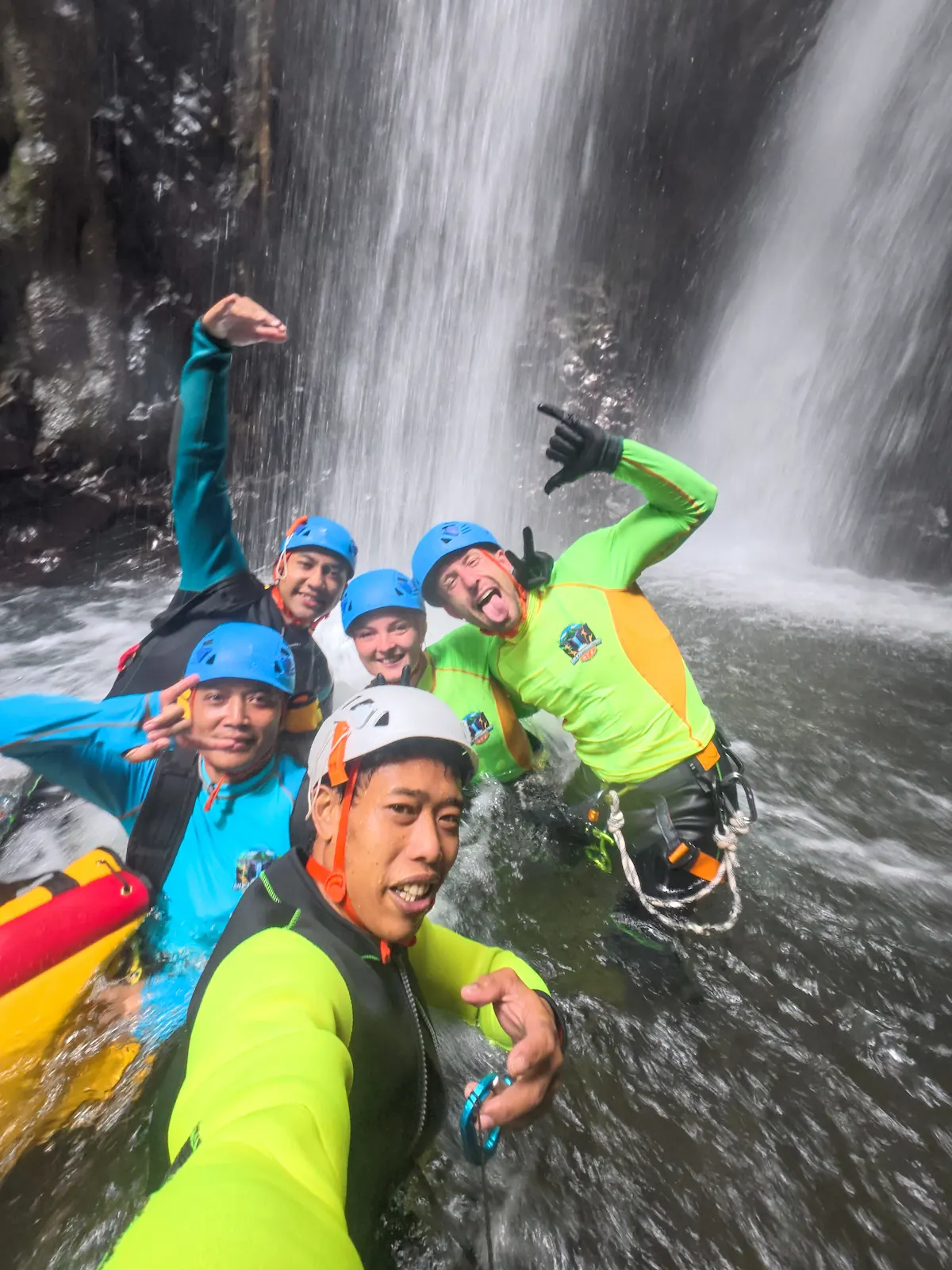 Group of canyoners cheering under a waterfall