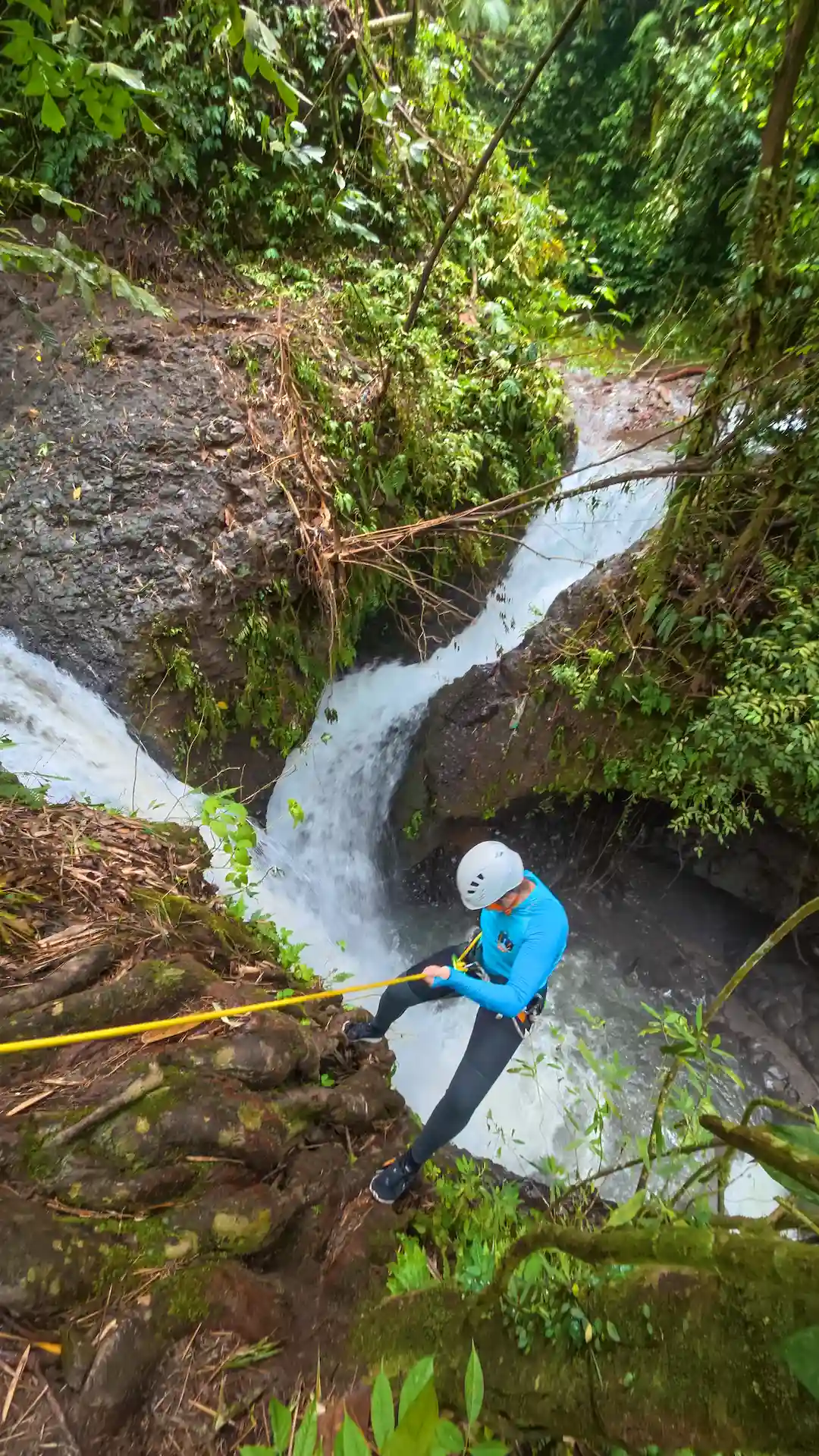 Canyoner descending a tall waterfall on rope