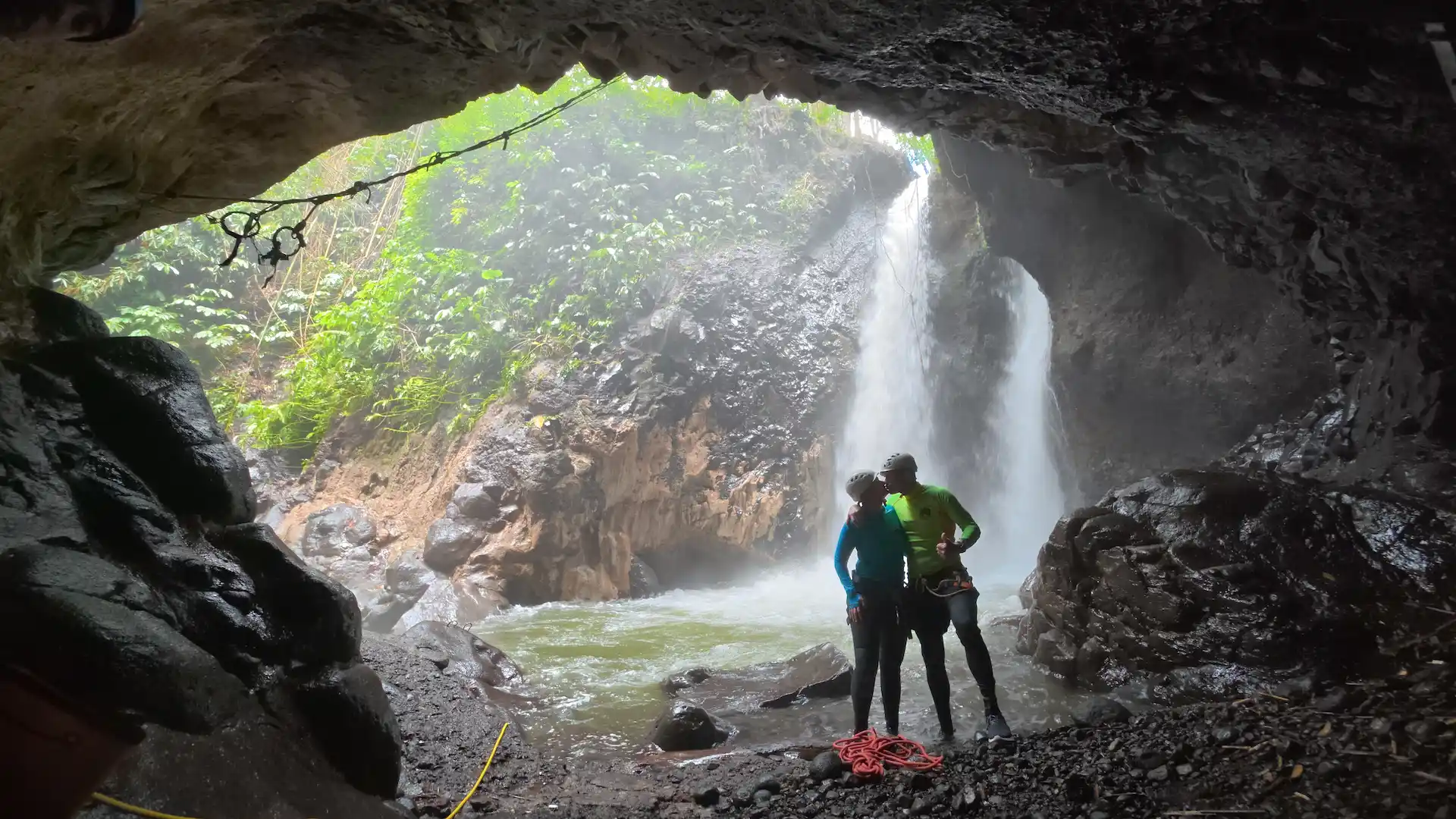 Twin waterfalls framed by a canyon cave opening