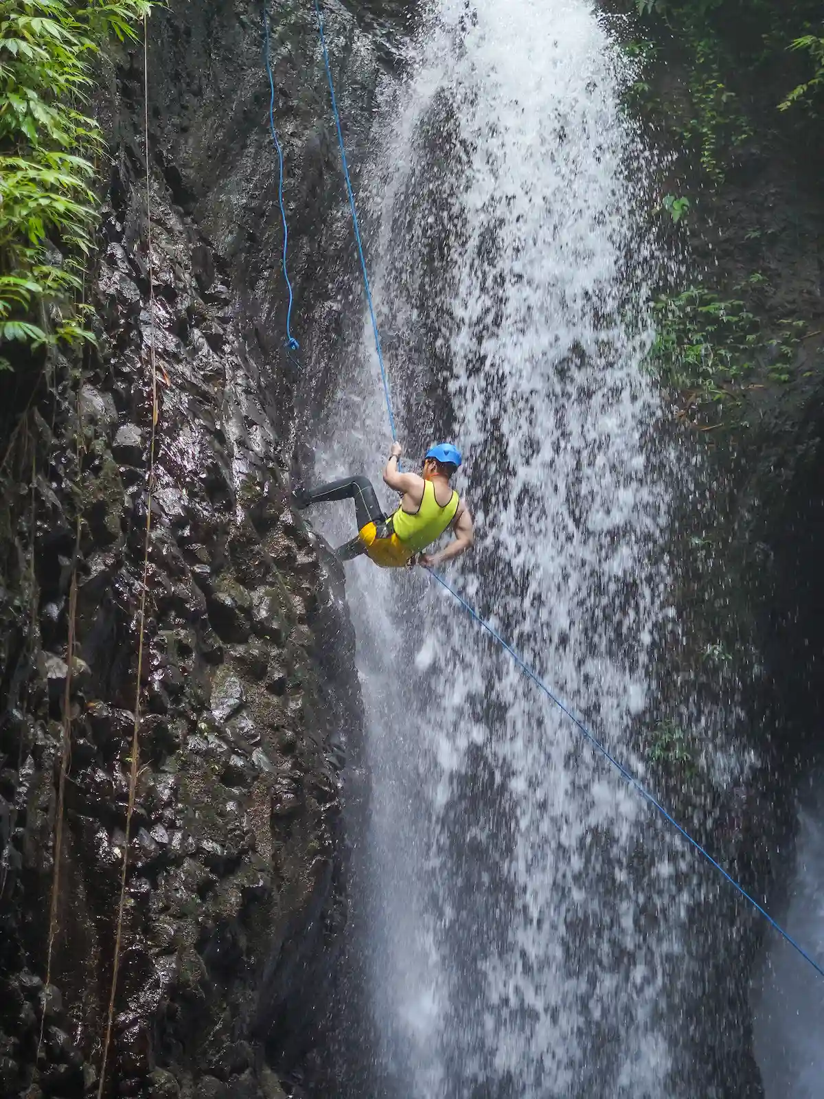 Guest rappelling down the waterfall on a rope, guided step by step