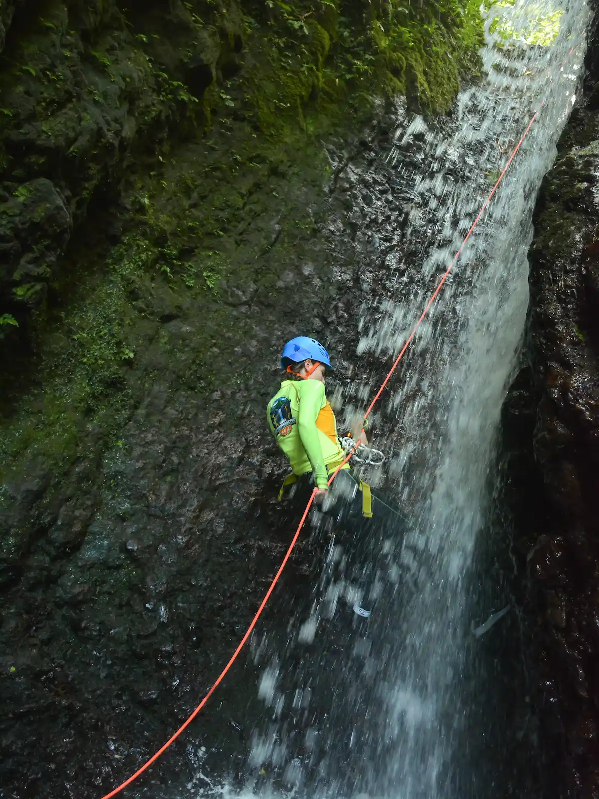 Guest rappelling a waterfall on a guide's rope on Splash Canyon