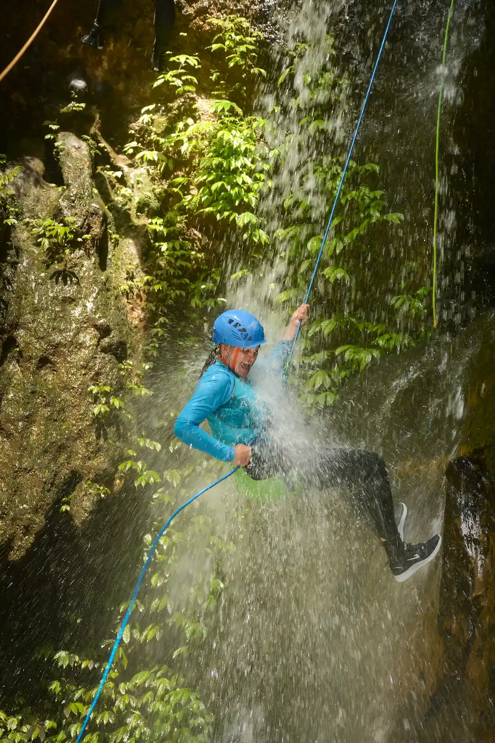 Guest rappelling through waterfall spray on Splash Canyon
