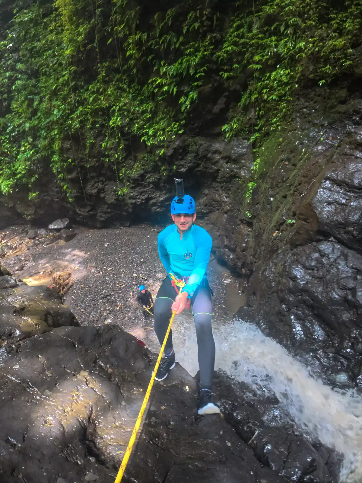 Guest descending a rope beside a canyon cascade on Splash Canyon
