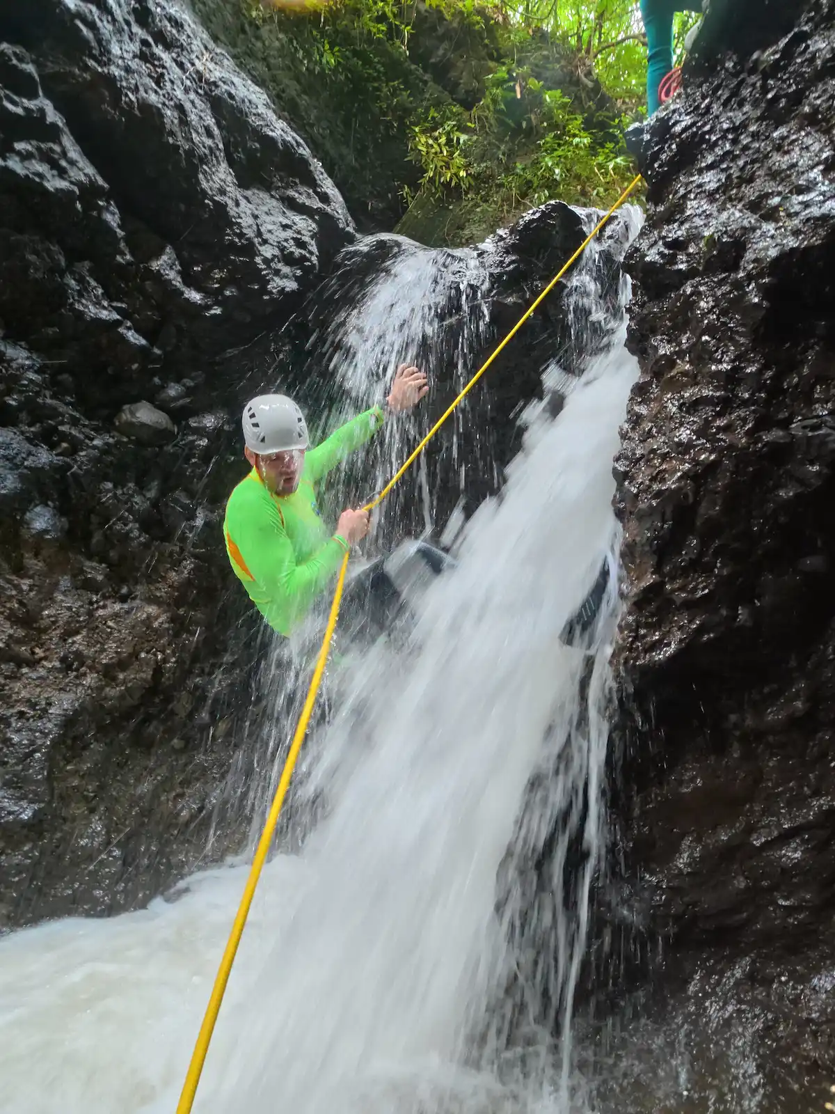 Guest rappelling straight into a waterfall on Splash Canyon