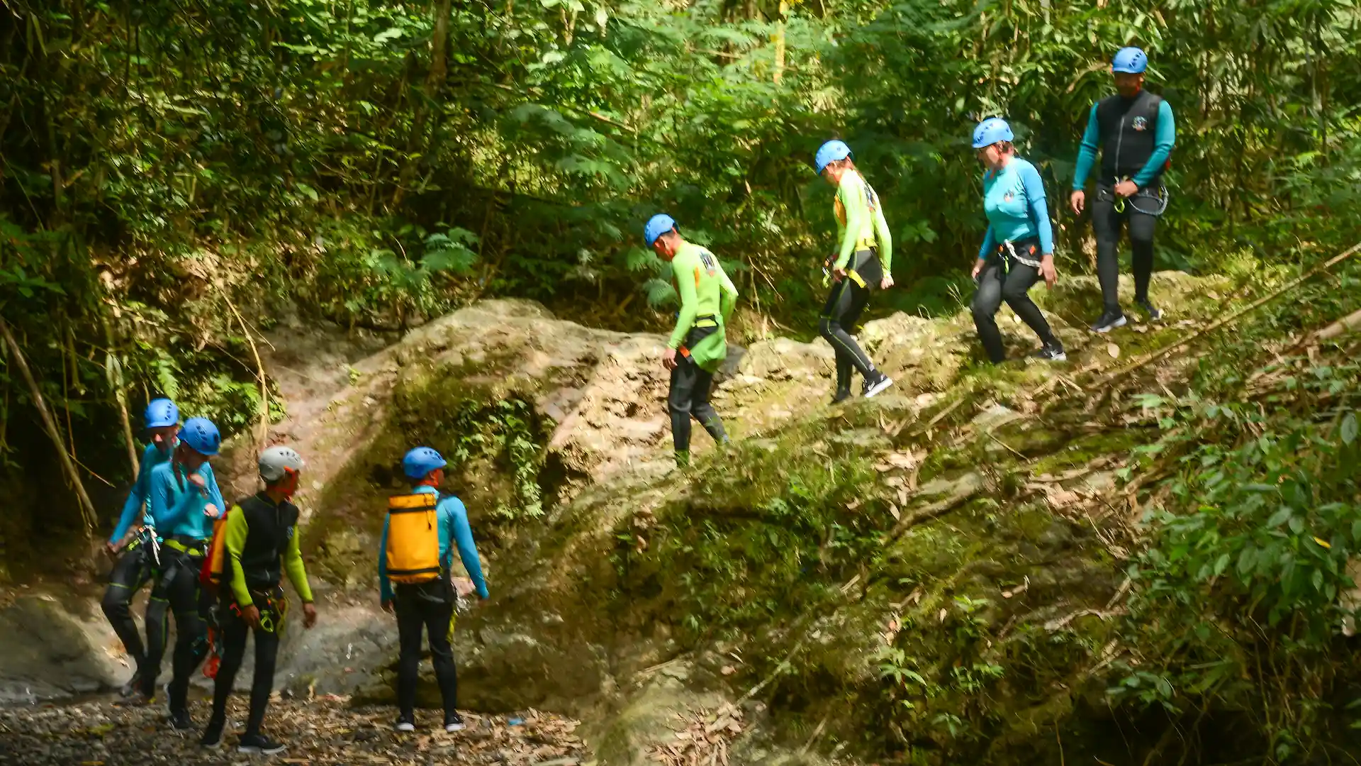 A guided canyoning group in helmets and wetsuits moving through a North Bali canyon