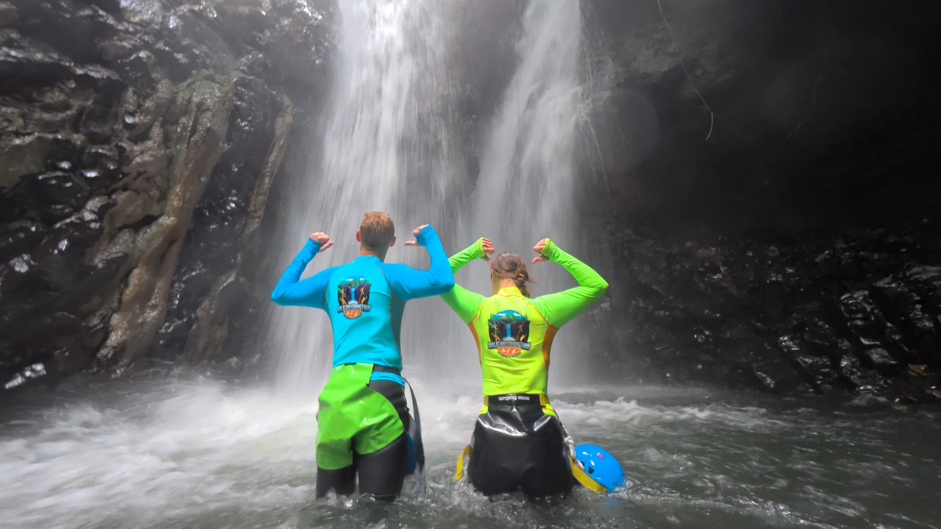 Two adventurers celebrating in front of a North Bali waterfall